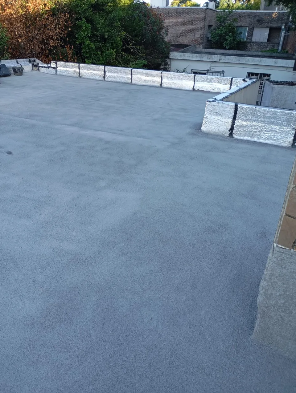 Azotea terminada en gris, con pretiles cubiertos con membrana aluminizada